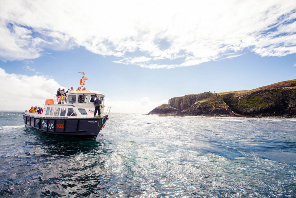 A boat of Staffa Tours off the shore of the Isle of Staffa in Scotland.